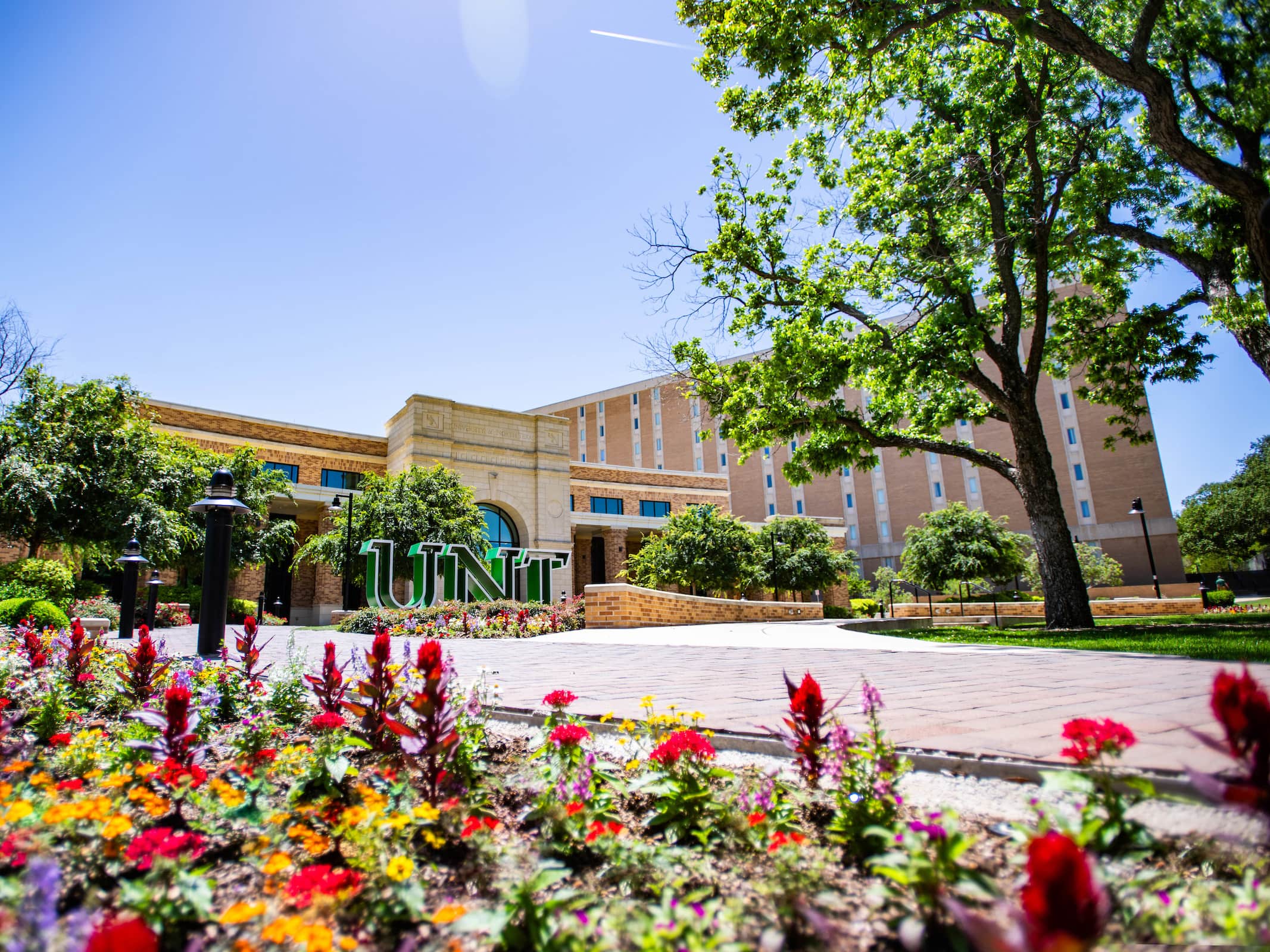 Photo of exterior of UNT Welcome Center with flowers in the foreground