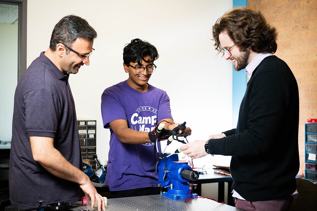 Photo of UNT professor Amir Jafari and his students working on a robotic glove in his lab.