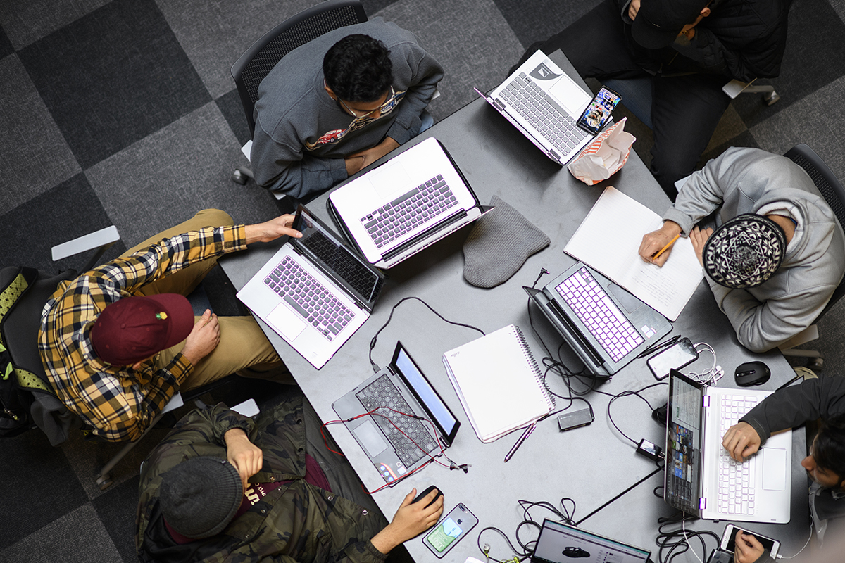 Photo of students working on computers at a table from above